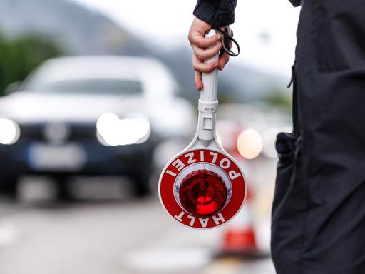 Ein Polizist steht im Mai an der Grenzkontrollstelle der Bundespolizei an der A 93 bei Kiefersfelden (Bayern) an der deutschen Grenze am Straßenrand der Autobahn und hält seine Kelle in der Hand. 