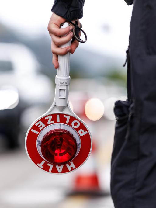 Ein Polizist steht im Mai an der Grenzkontrollstelle der Bundespolizei an der A 93 bei Kiefersfelden (Bayern) an der deutschen Grenze am Straßenrand der Autobahn und hält seine Kelle in der Hand. 