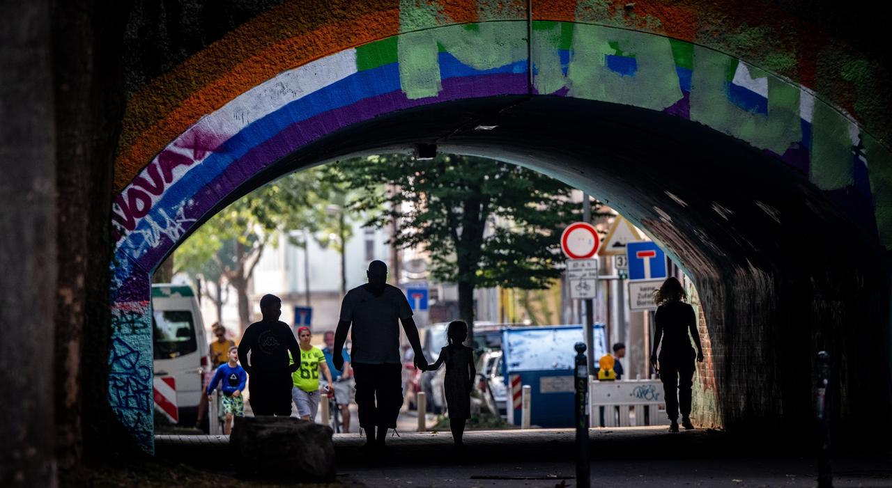 Fußgänger laufen unter einer mit Graffiti besprühten Brücke in der Dortmunder Nordstadt, 17. August 2022.