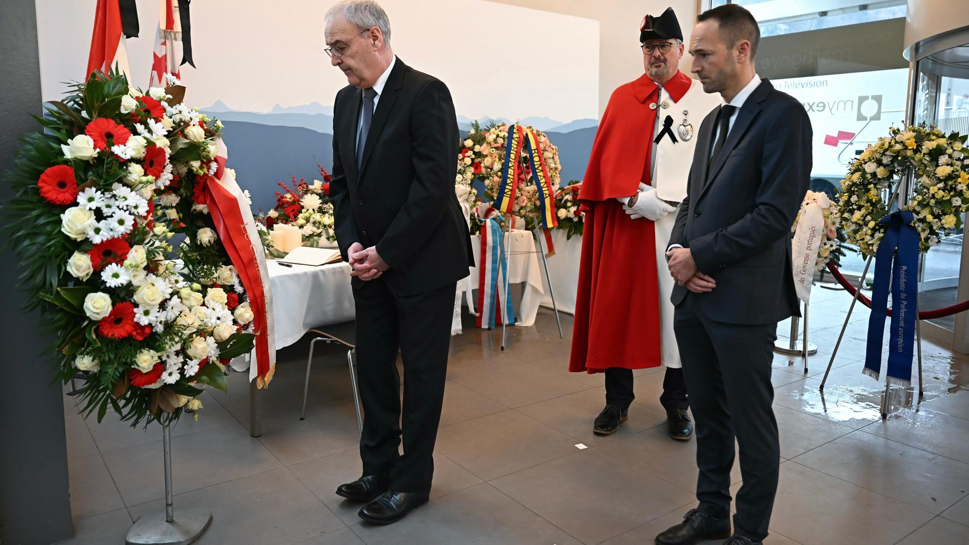 Martigny: Der Schweizer Bundespräsident Guy Parmelin (l) und Mathias Reynard, Staatsrat und Präsident des Staatsrats des Kantons Wallis (r), erweisen während der Trauerfeier für die Opfer vor einem Kranz die Ehre.
