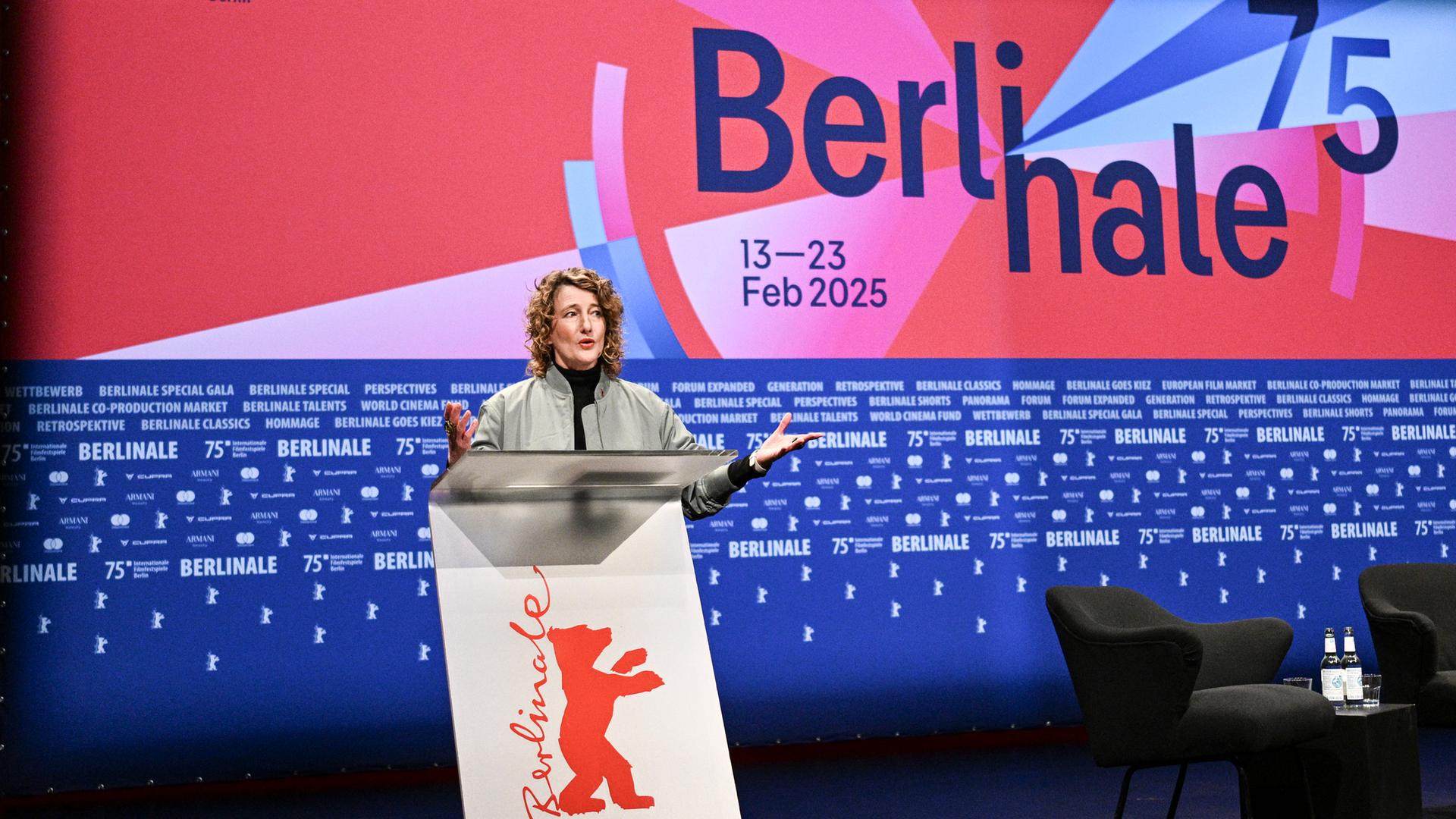 Berlinale-Chefin Tricia Tuttle steht hinter einem Rednerpult. Der Hintergrund ist blau und rot mit der Aufschrift "Berlinale 75".