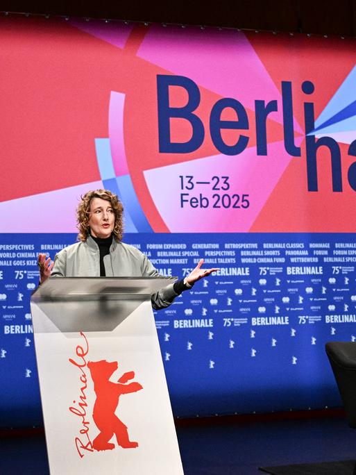 Berlinale-Chefin Tricia Tuttle steht hinter einem Rednerpult. Der Hintergrund ist blau und rot mit der Aufschrift "Berlinale 75".