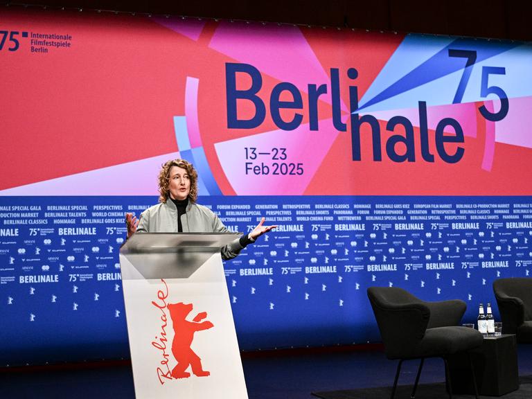 Berlinale-Chefin Tricia Tuttle steht hinter einem Rednerpult. Der Hintergrund ist blau und rot mit der Aufschrift "Berlinale 75".