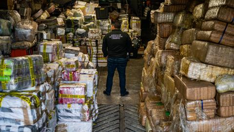 Ein mexikanischer Kriminalbeamter steht inmitten eines Lagers mit beschlagnahmtem Fentanyl und Meth in folienumwickelten Paketen.