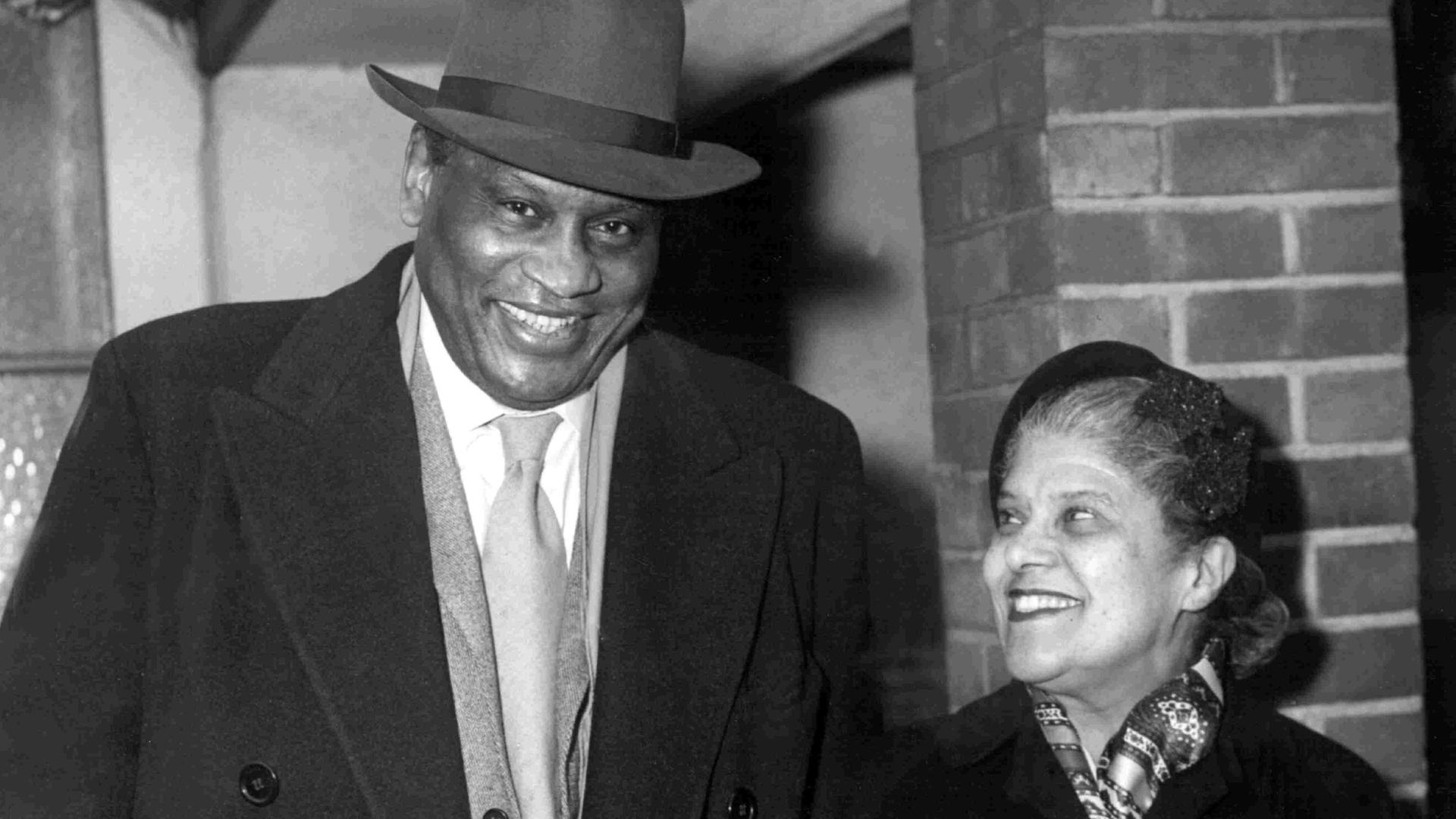 Der amerikanische Sänger und Sozialkritiker Paul Robeson mit seine Frau Eslanda Cardoza Goode am 23. Dezember 1958 auf dem Londoner Flughafen. Der amerikanische Sänger und Sozialkritiker Paul Robeson mit seine Frau Eslanda Cardoza Goode am 23. Dezember 1958 auf dem Londoner Flughafen.