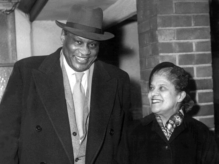 Der amerikanische Sänger und Sozialkritiker Paul Robeson mit seine Frau Eslanda Cardoza Goode am 23. Dezember 1958 auf dem Londoner Flughafen.