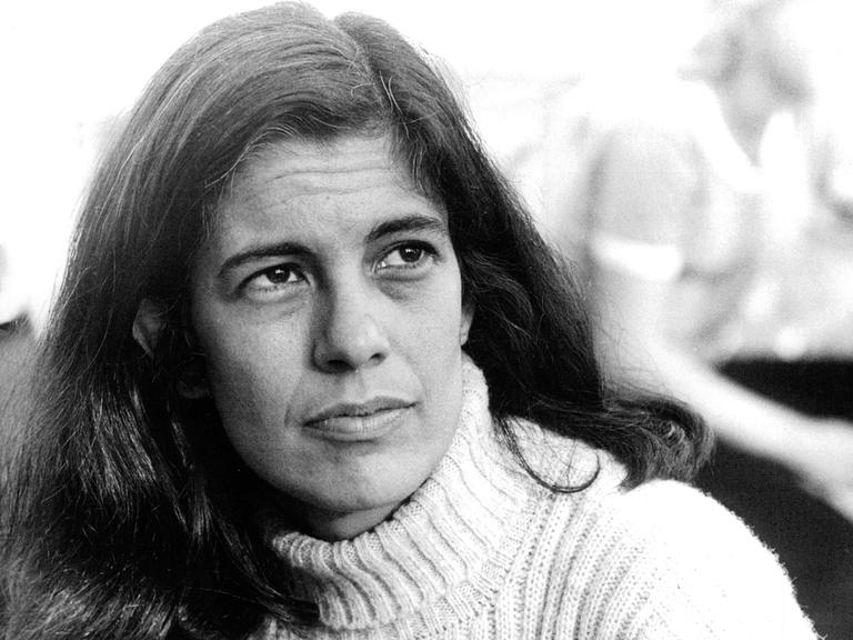 Schwarzweißporträt von Susan Sontag, die mit ernster Miene ins Off des Bildes blickt.