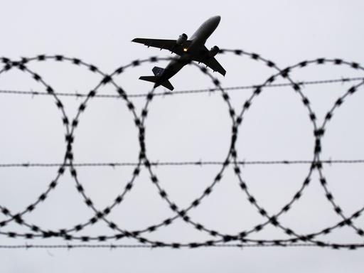 Ein Flugzeug von Lufthansa startet am Flughafen Hannover - fotografiert durch Stacheldraht am Flughafenzaun.