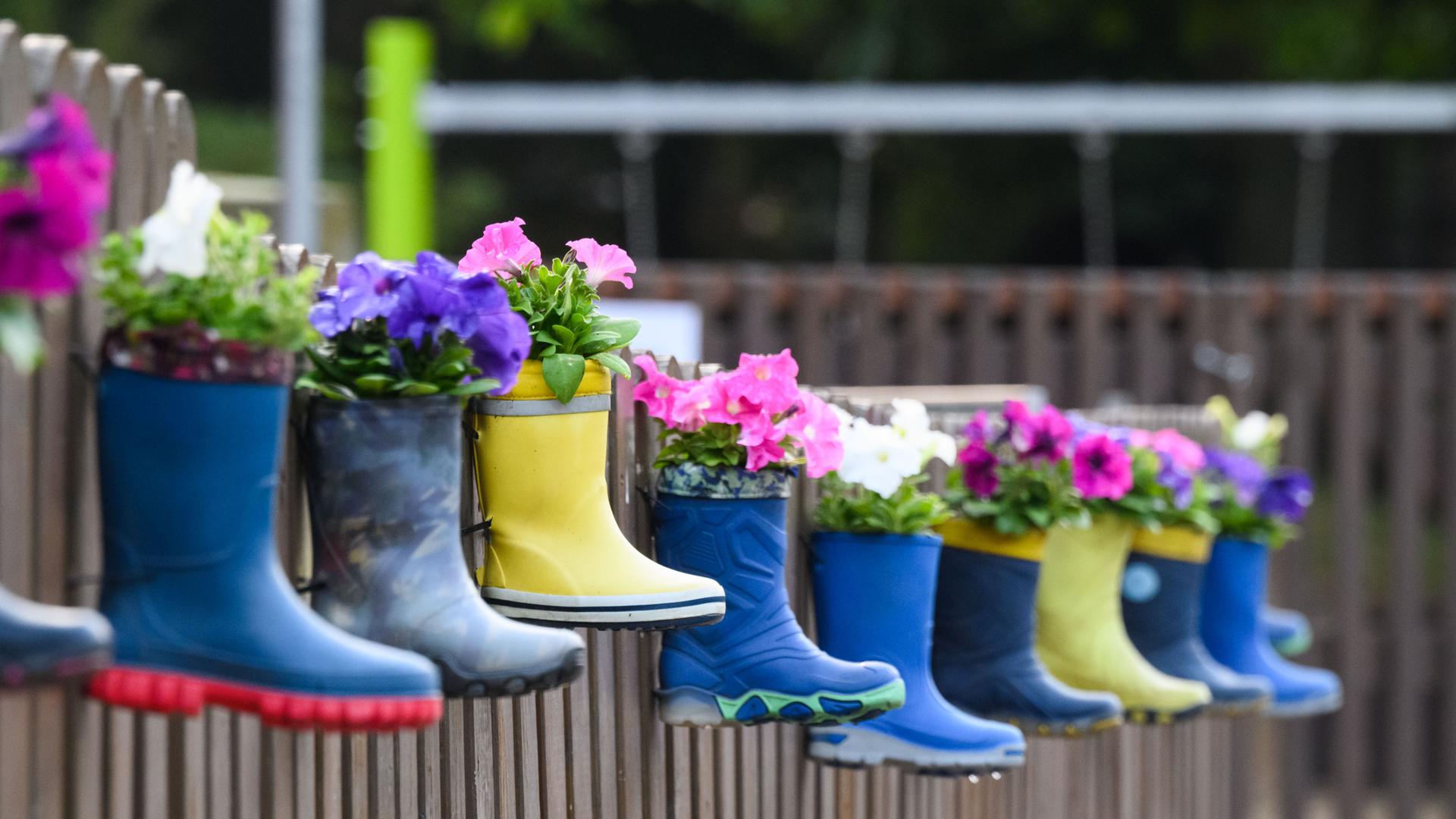 Gummistiefel von Kindern mit Blumen hängen am Zaun eines Kindergartens in der Region Hannover. Gummistiefel von Kindern mit Blumen hängen am Zaun eines Kindergartens in der Region Hannover.