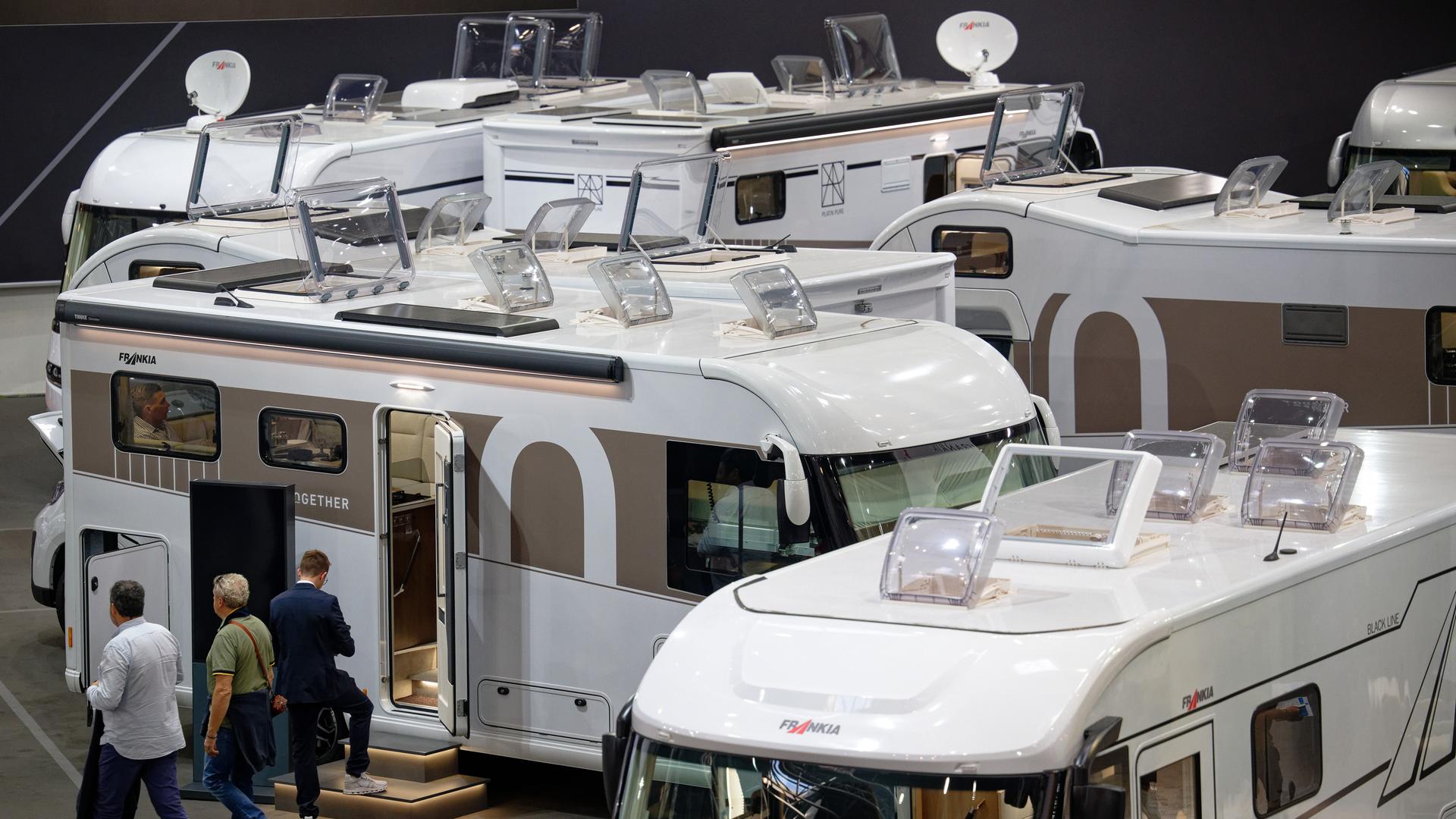 Besucher gehen beim "Caravan Salon - Messe für Caravaning, Camping und Outdoor-Tourismus" durch Hallen mit Campingmobilen. 