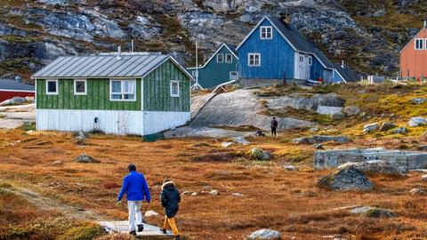 Das Foto zeigt bunte historische Holzhäuser im kleinen, abgelegenen Inuit-Dorf Aappilattoq inSüdgrönland.