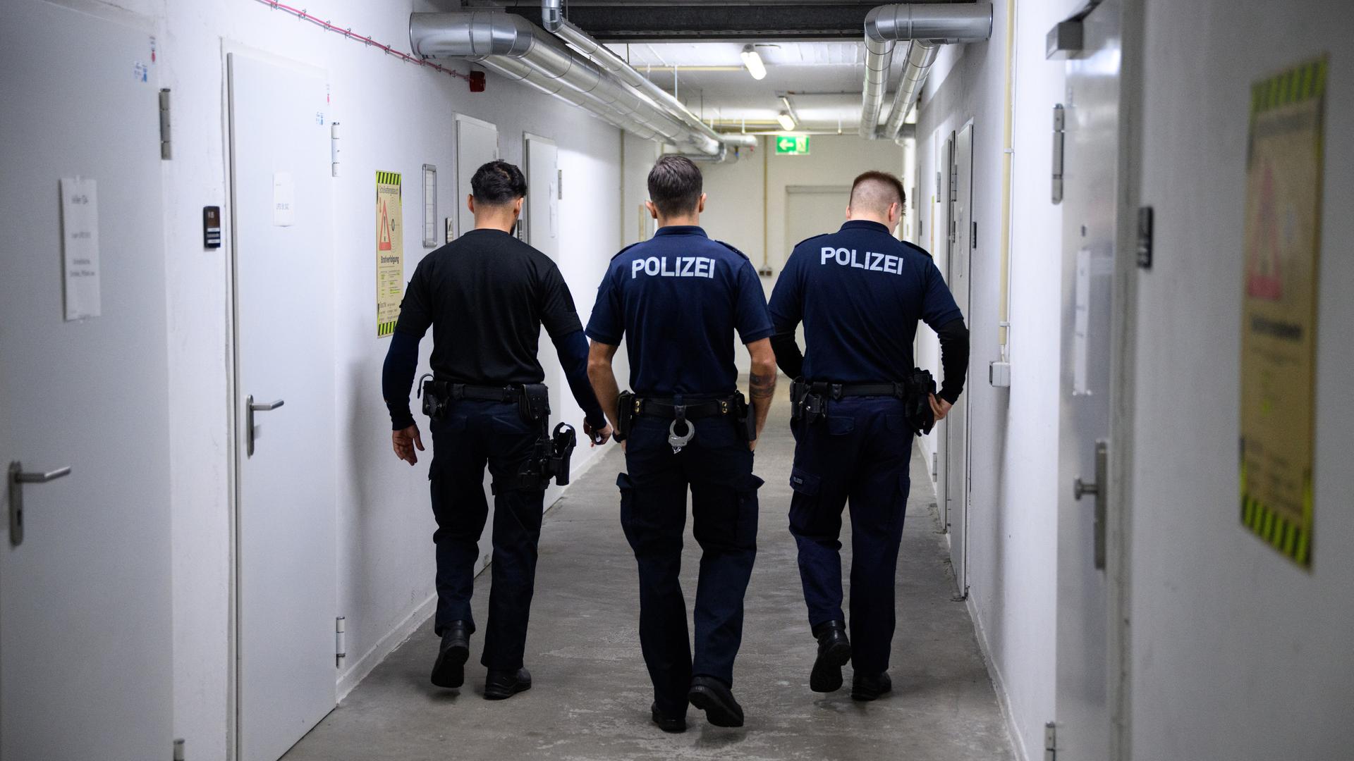 Drei Polizeibeamte von hinten fotografiert im Keller Ihres Dienstsitzes Drei Polizeibeamte von hinten fotografiert im Keller Ihres Dienstsitzes