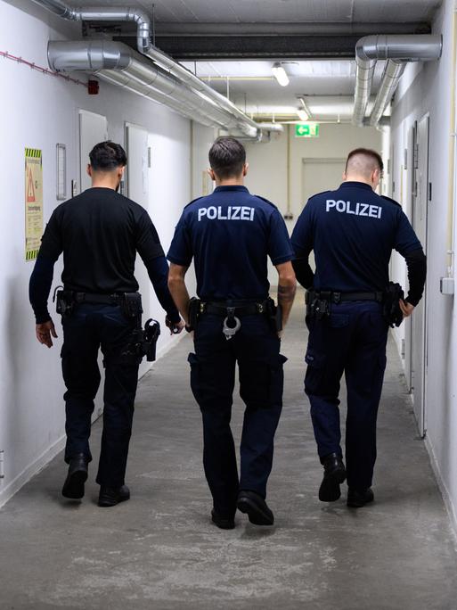 Drei Polizeibeamte von hinten fotografiert im Keller Ihres Dienstsitzes 