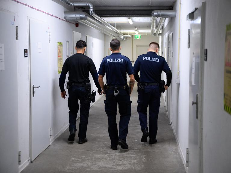 Drei Polizeibeamte von hinten fotografiert im Keller Ihres Dienstsitzes 