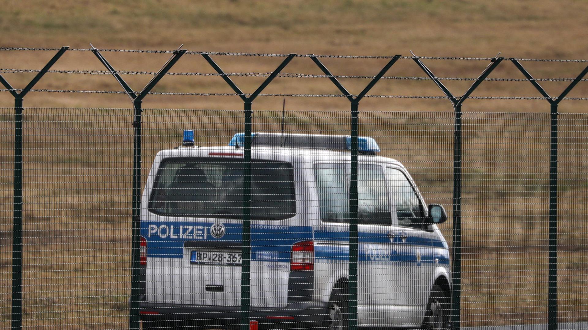 Ein Fahrzeugn der Bundespolizei fährt hinter einem Stacheldrahtzaun auf dem Geländes des Flughafen Dresden International Streife.
