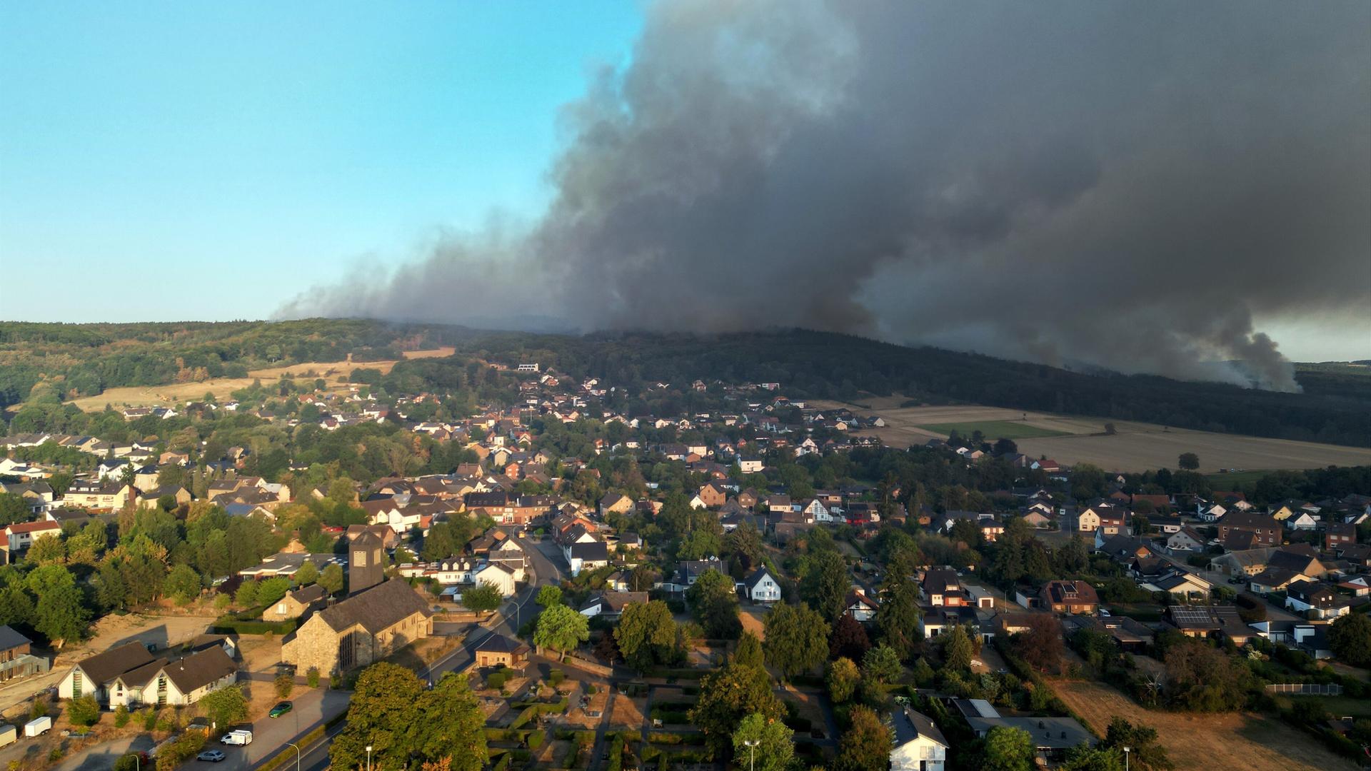 Dichter Rauch von einem Wald-Brand zieht über die Häuser von einem kleinen Ort. Das Foto ist von einer Drohne gemacht worden. 
