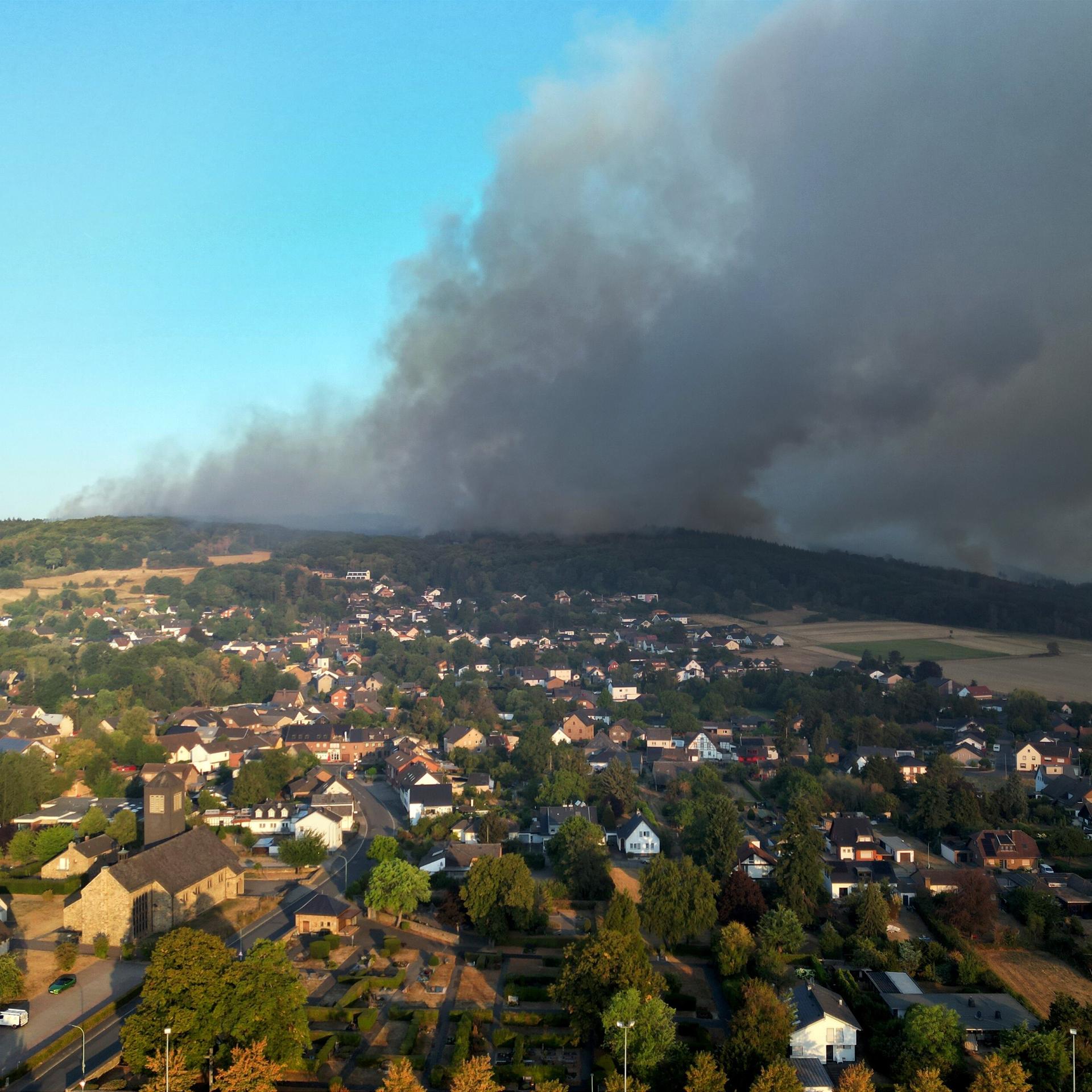 Dichter Rauch von einem Wald-Brand zieht über die Häuser von einem kleinen Ort. Das Foto ist von einer Drohne gemacht worden. 
