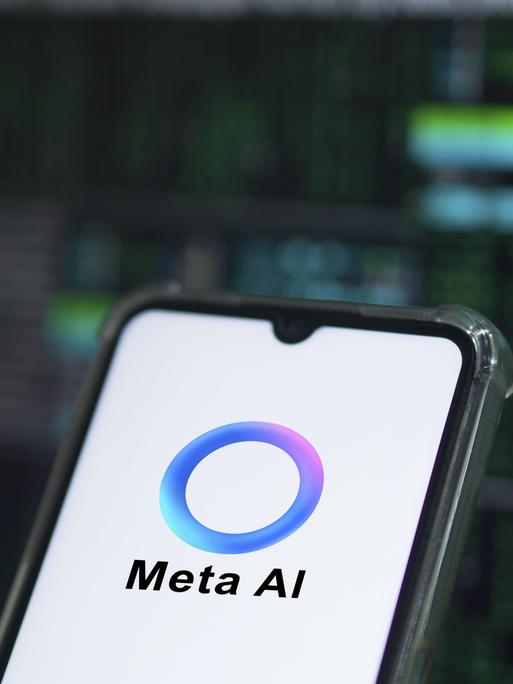 Auf einem Smartphone ist das Logo von Meta AI zu sehen: Ein überwiegend blauer Ring, der an manchen Stellen in Lila- und Grüntöne übergeht. 