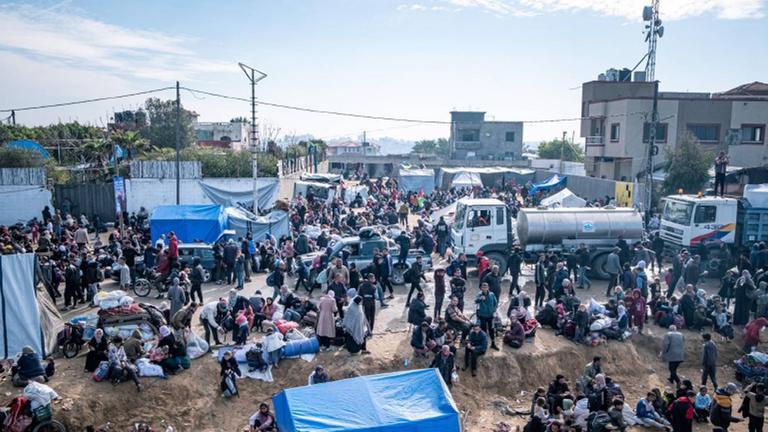 Menschen versammeln sich in Gaza in der Nähe von Zelten und LKW mit Hilfsgütern. Foto von CADUS | Mattia Bidoli.