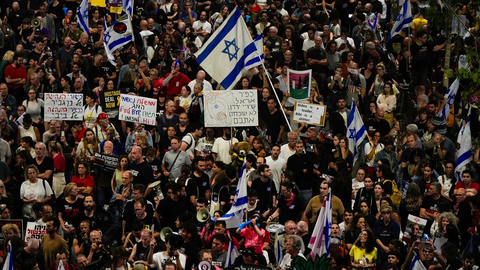 Aus einer Menschenmasse heraus werden Israel-Flaggen geschwenkt und Plakate hochgehalten.
