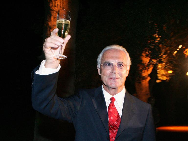 Archivbild: Franz Beckenbauer hält ein Glas Sekt in der Hand und prostet in die Luft.