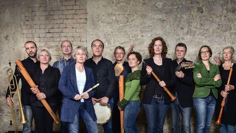 Mitglieder der Capella de la Torre stehen an einer historischen Ziegelwand mit ihren Instrumenten.