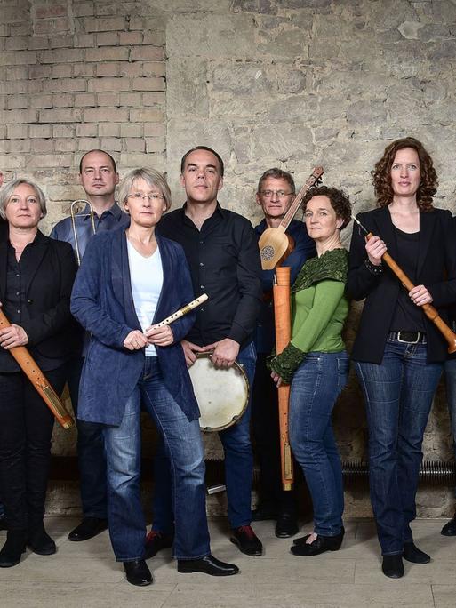 Mitglieder der Capella de la Torre stehen an einer historischen Ziegelwand mit ihren Instrumenten.