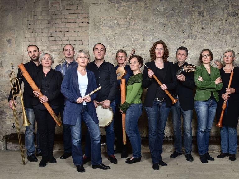 Mitglieder der Capella de la Torre stehen an einer historischen Ziegelwand mit ihren Instrumenten.