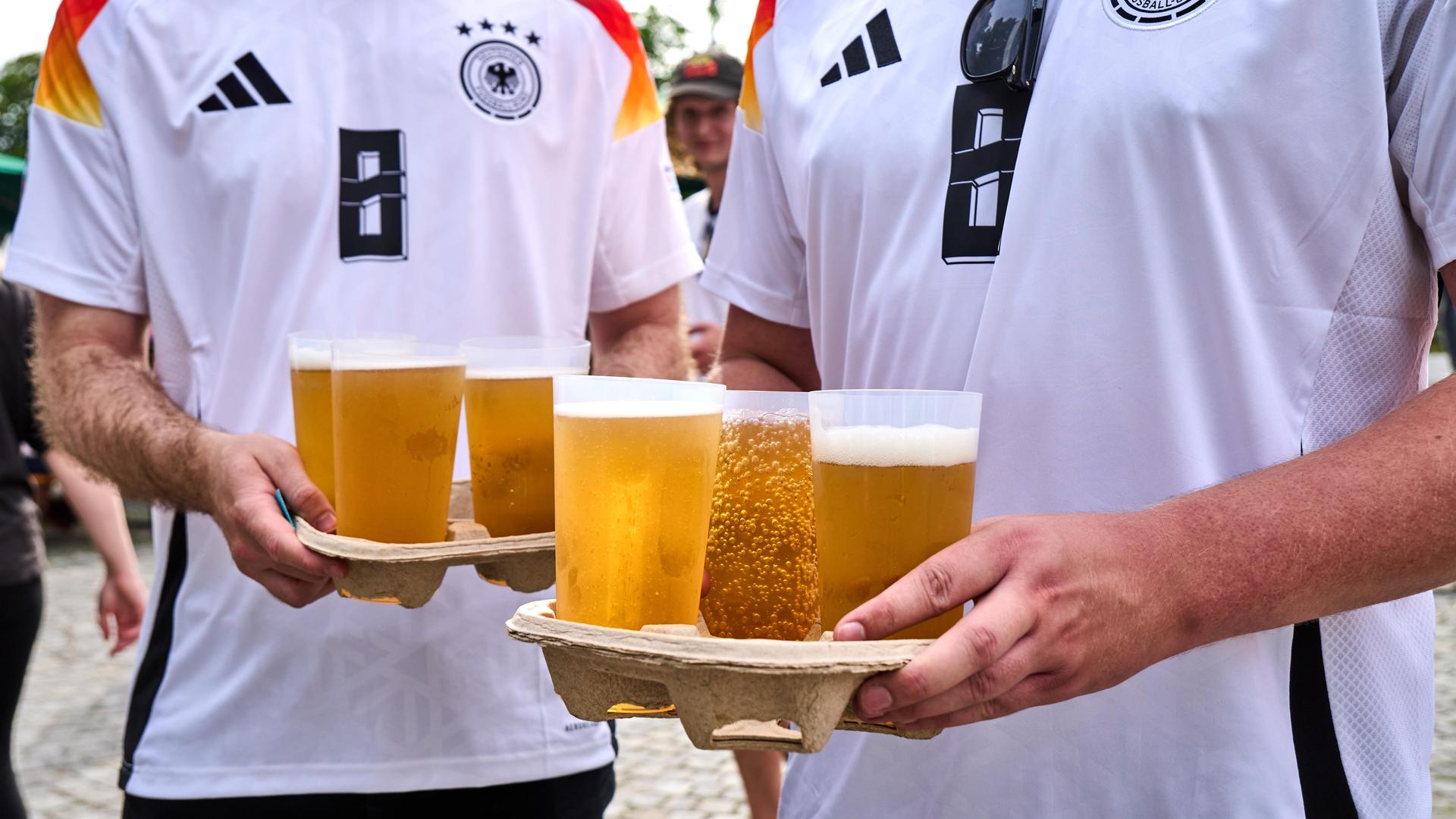 Deutsche Fußballfans mit mehreren Bechern Bier im Olympiapark München