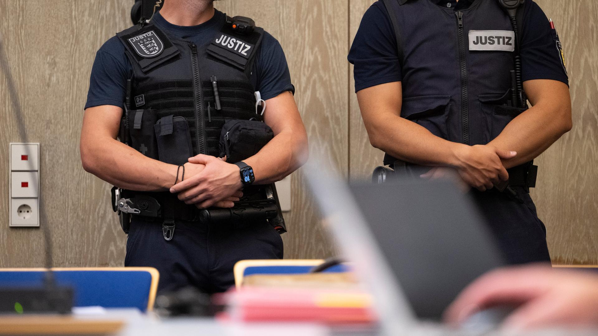 Justizbeamte stehen beim Auftakt im Prozess gegen drei junge, mutmaßliche IS-Sympathisanten in einem Saal des Landgerichts Mannheim.