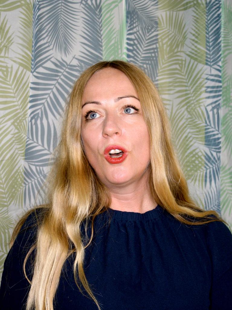 Die Profi-Jodlerin Doreen Kutzke formt den Mund zum Gesang. Sie hat lange blonde Haare und trägt eine dunkelblaue Bluse. Sie steht vor einem grünlich gemusterten Vorhang.