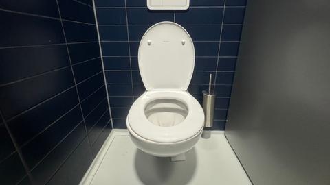 Eine Kloschüssel in einer Toilette mit offenem Deckel
