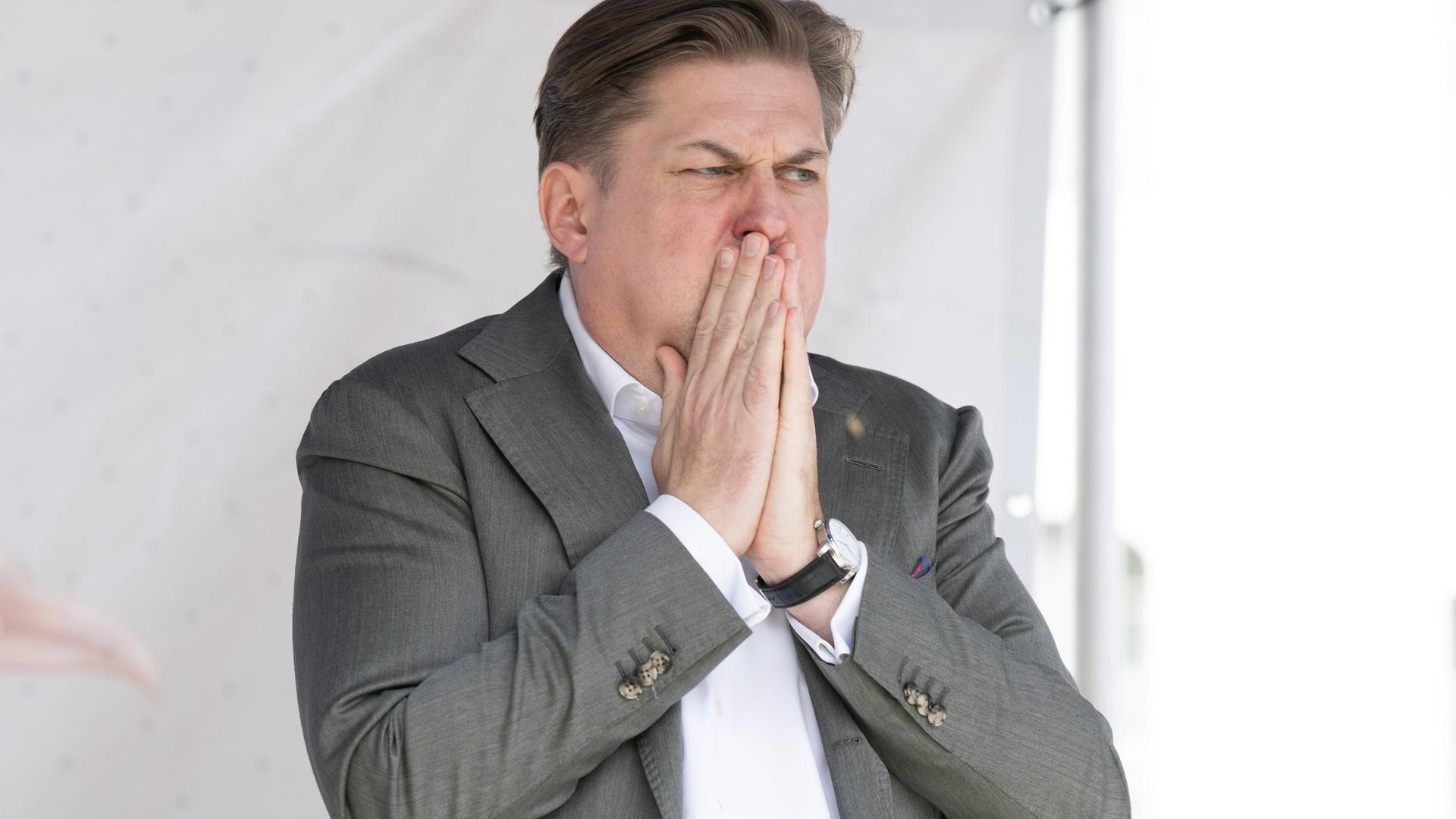 Maximilian Krah, AfD-Spitzenkandidat für die Europawahl, steht auf einer Bühne und bedeckt den Mund mit den Händen.