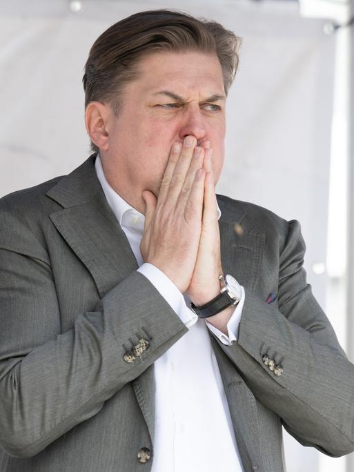 Maximilian Krah, AfD-Spitzenkandidat für die Europawahl, steht auf einer Bühne und bedeckt den Mund mit den Händen.