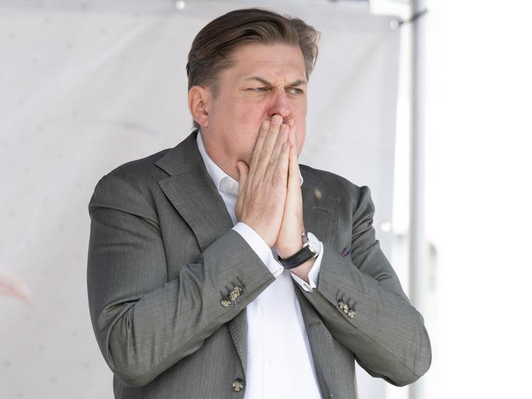 Maximilian Krah, AfD-Spitzenkandidat für die Europawahl, steht auf einer Bühne und bedeckt den Mund mit den Händen.