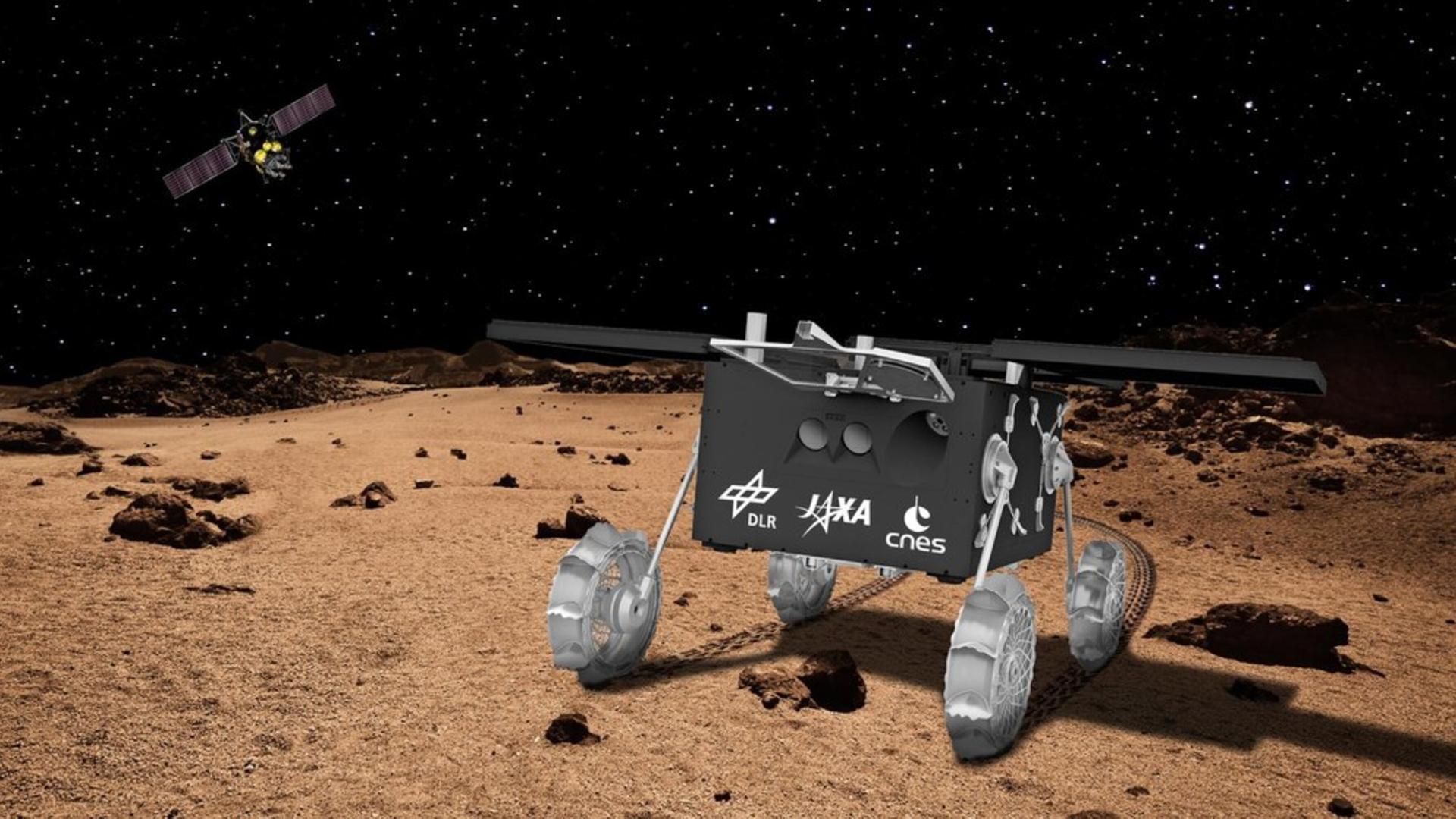 Eine Illustration zeigt einen Rover auf brauner Erde und im dunklen Himmel fliegt das MMX-Mutterschiff 