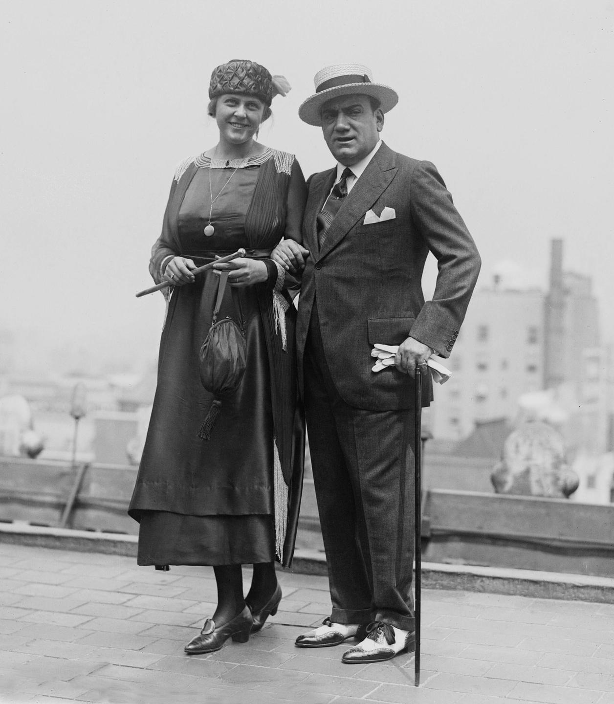 Enrico Caruso steht mit seiner Frau vor einer verschwommenen Häuserkulisse in New York.