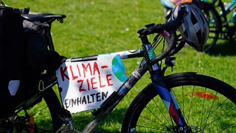 Ein Schild mit der Aufschrift "Klima-Ziele einhalten" hängt an einem Fahrrad.