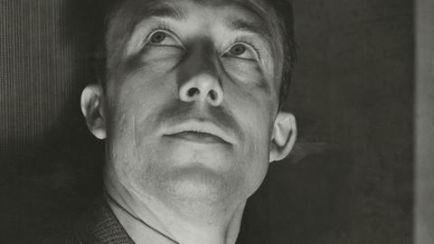 Schwarzweißaufnahme von Alber Camus, der freundlich nach oben schaut.