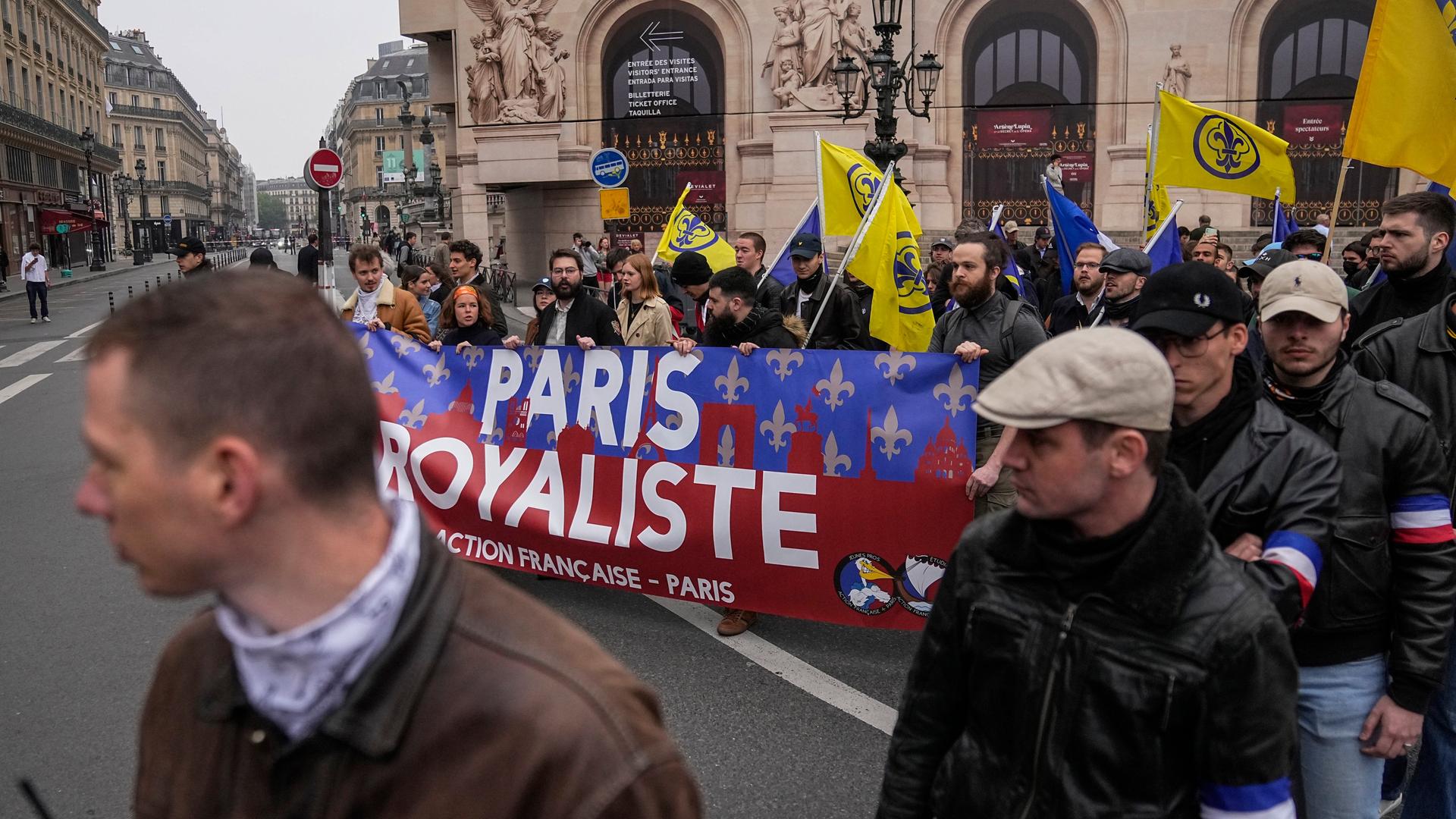 Zahlreiche Personen laufen durch Paris. Sie tragen ein Banner mit der Aufschrift "Paris royaliste". Zahlreiche Personen laufen durch Paris. Sie tragen ein Banner mit der Aufschrift "Paris royaliste".