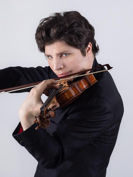 Ein Mann spielt eine Violine, der Blick richtet sich direkt in die Kamera.