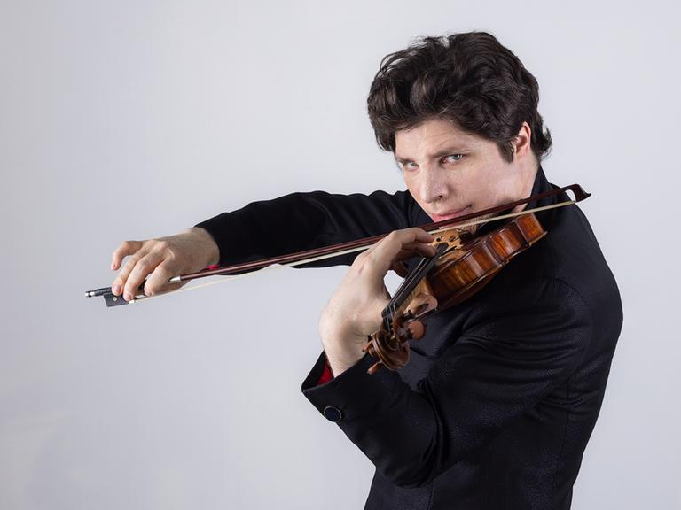 Ein Mann spielt eine Violine, der Blick richtet sich direkt in die Kamera.