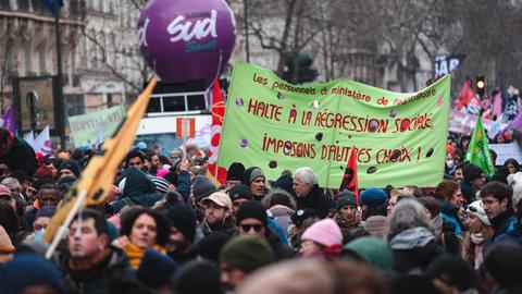 Demonstrators hold a banner with the slogan 'Stop social regression, let's impose other choices!' during the demonstration which brought together tens of thousands of people who take part in a demonstration in Paris on January 19, 2023, as workers go on strike against the pension reform project presented by the French government to increase the legal retirement age from 62 to 64 years.