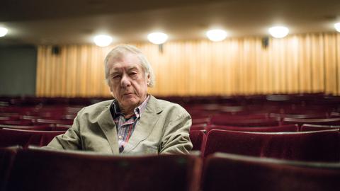 Regisseur Hans Neuenfels sitzt am 04.06.2015 nach einem Interview zu seiner Inszenierung von "Ariadne auf Naxos" in der Staatsoper im Schillertheater in einer roten Sitzreihe im Zuschauerraum.