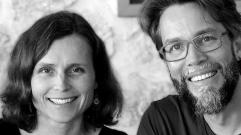 Anna und Patrick Hemminger sitzen an einem Esstisch und lächeln.