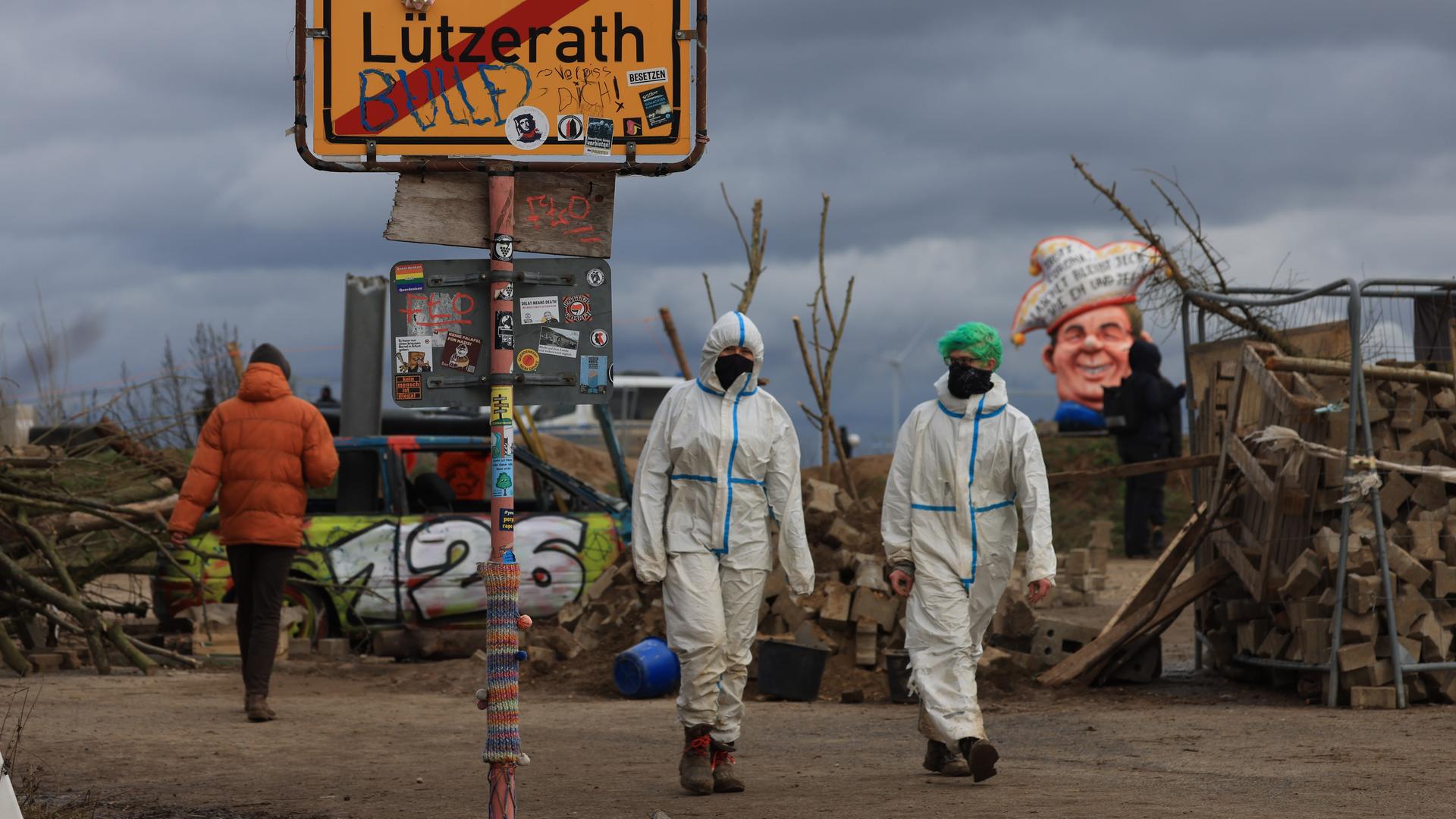 Klimaschutzaktivisten gehen an einem Schild mit der Aufschrift Lützerath vorbei.. Das Dorf Lützerath soll zur Erweiterung des Braunkohletagebaus Garzweiler II abgebaggert werden.