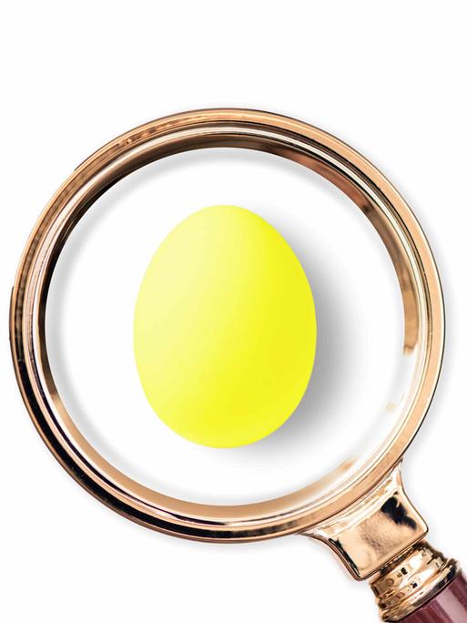 Ein gelbes Osterei unter einer großen Lupe