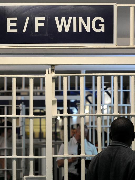 In einem Gefängnistrakt in Großbritannien stehen sich zwei Männer hinter Gittertüren gegegnüber. In einem Gefängnistrakt in Großbritannien stehen sich zwei Männer hinter Gittertüren gegegnüber.
