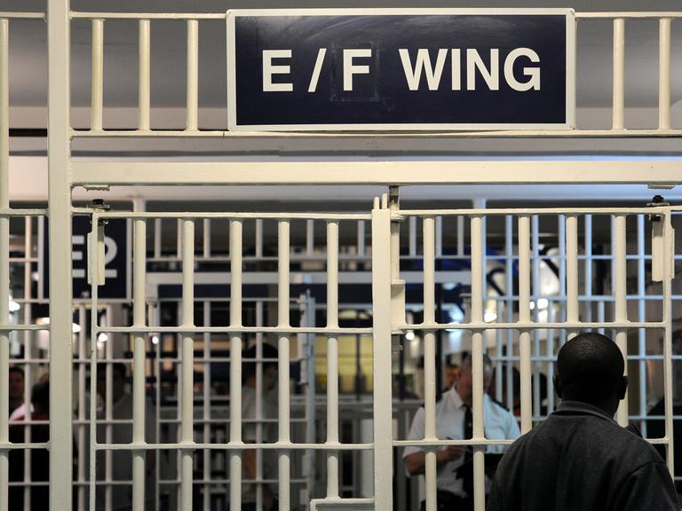 In einem Gefängnistrakt in Großbritannien stehen sich zwei Männer hinter Gittertüren gegegnüber. In einem Gefängnistrakt in Großbritannien stehen sich zwei Männer hinter Gittertüren gegegnüber.