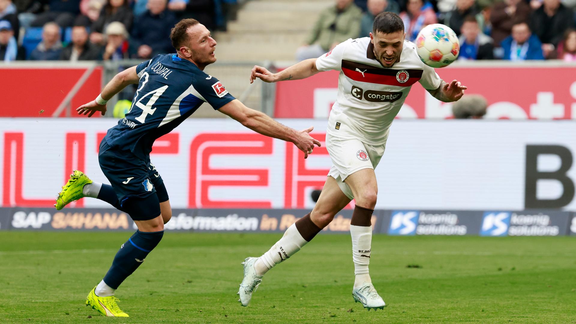 Das Bild zeigt zwei Fußballspieler im Kampf um den Ball, einer von beiden köpft den Ball Richtung Tor ins Netz.
